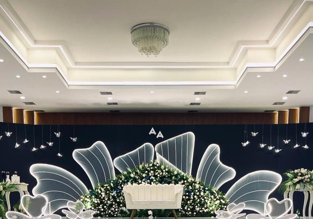 Dark navy wedding stage with acrylic floral panels and warm uplighting